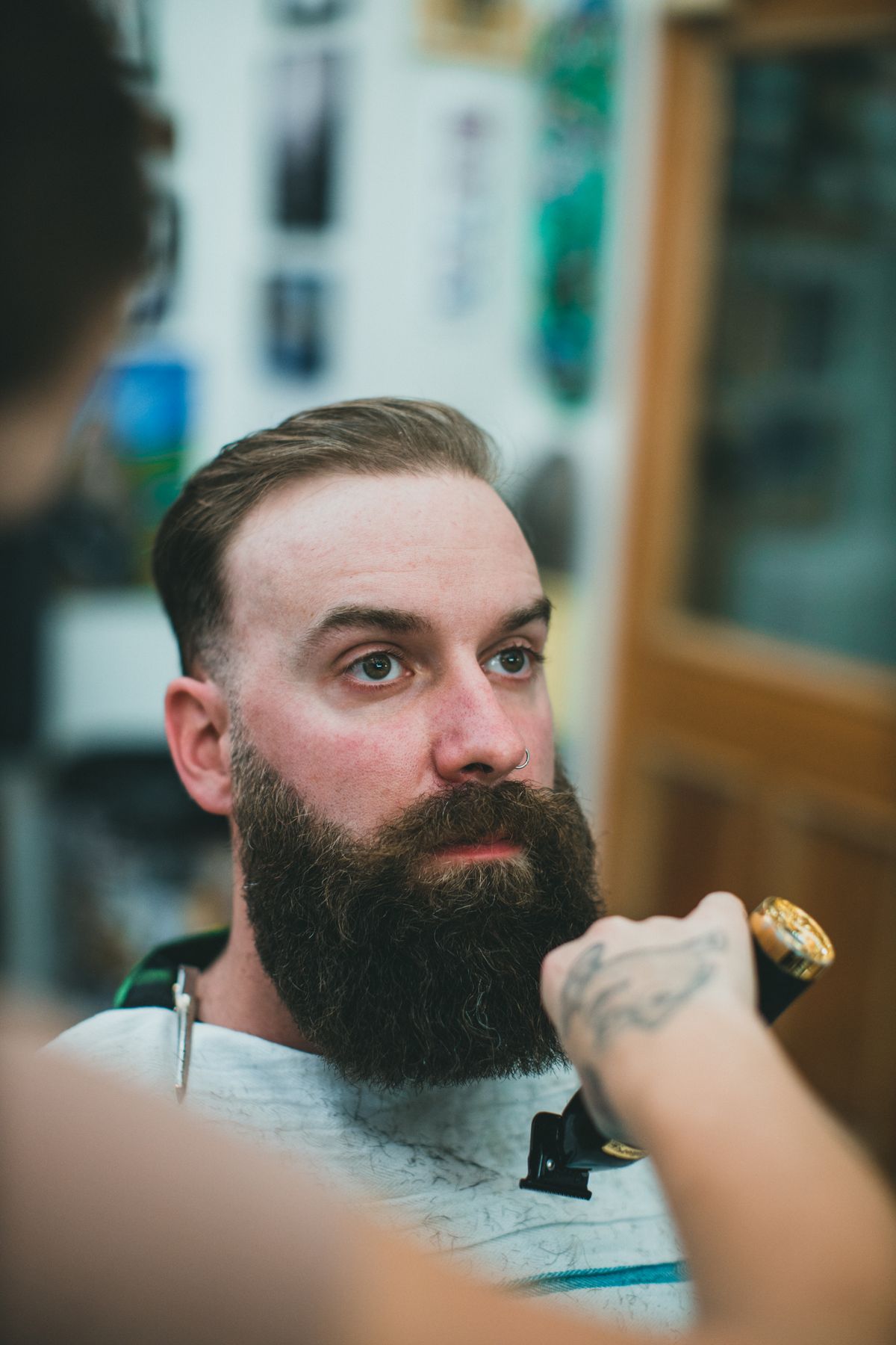 Stockfoto: Mann mit kurzem Haar und vollem Bart beim Trimmen im Barbershop