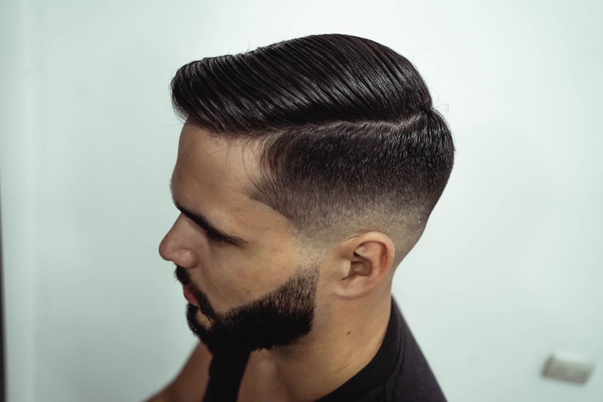 Stockfoto: Mann mit Fade, Seitenscheitel und präzise konturiertem Bart