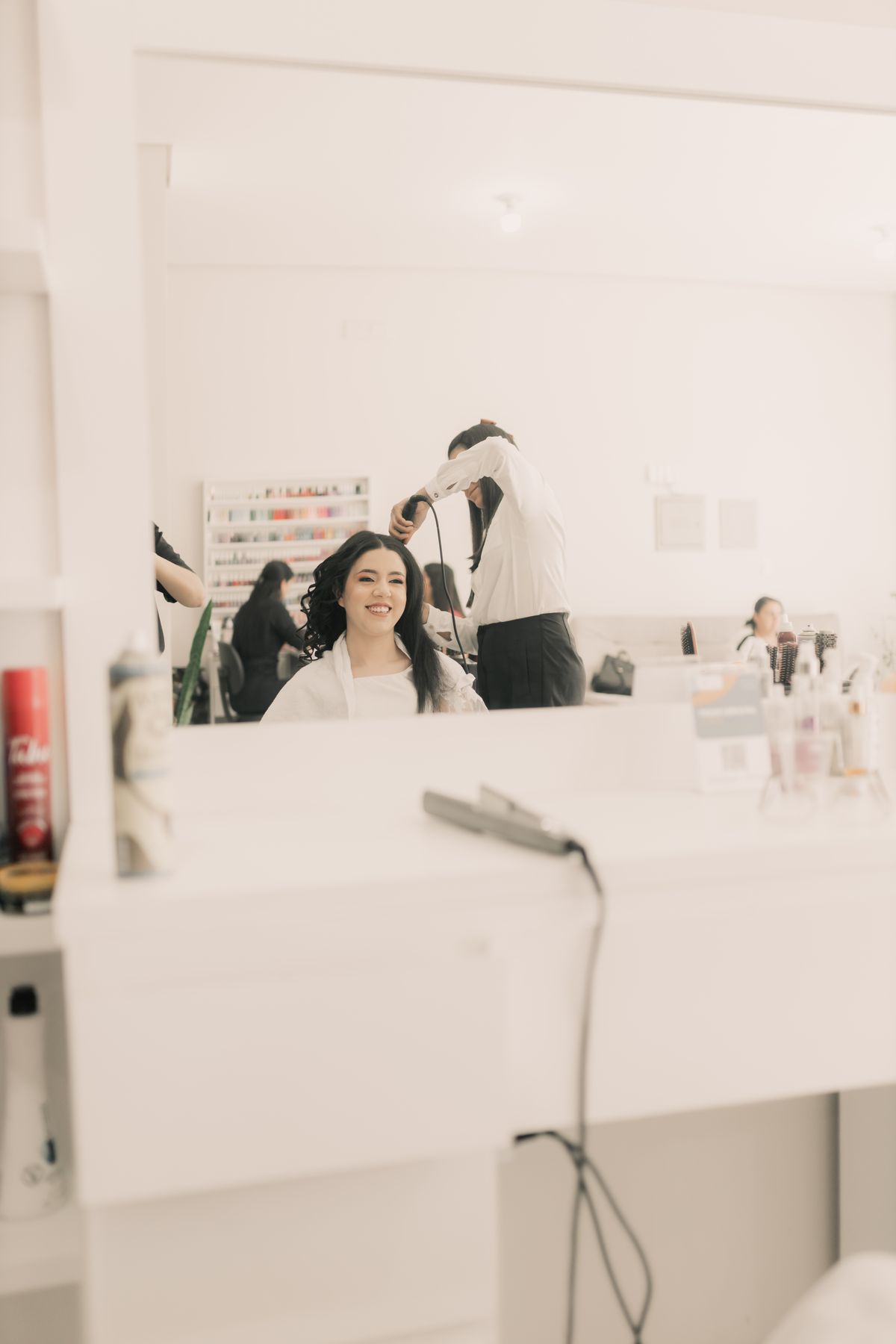 Stockfoto: Frau mit langem dunklem Haar beim Lockenstyling im Salon