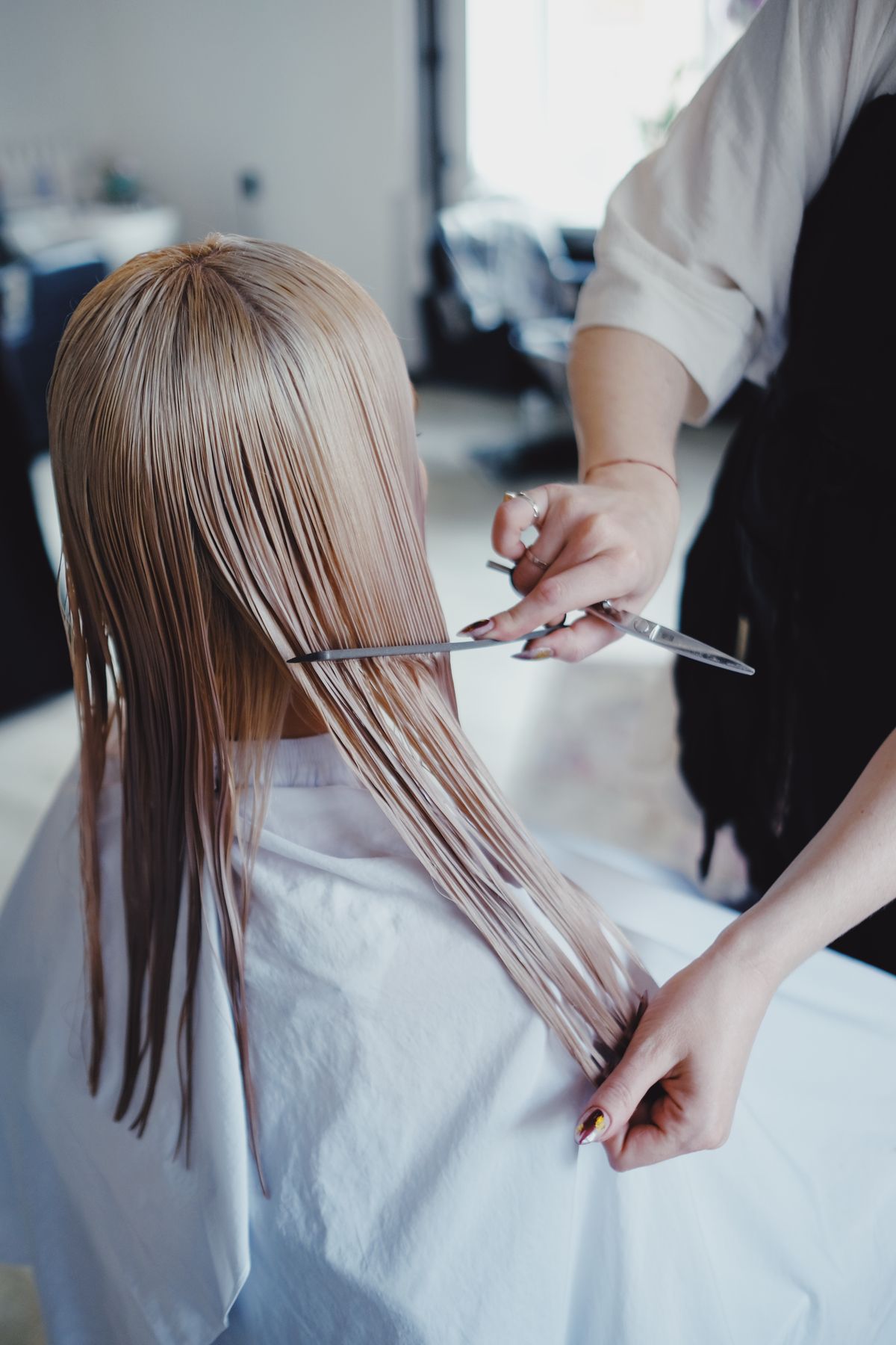 Stockfoto: Friseurin schneidet langes blondes Haar mit einer Schere